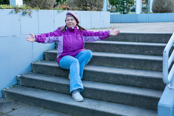 Obraz premium mature woman in bright pink jacket and beret sitting on concrete steps outdoors, thoughtful mature woman sitting alone, contemplative pause, looking away pause or waiting moment urban background