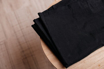 Black folded fabric on wooden table, minimal textile background