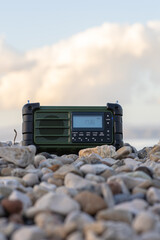 Rugged Portable Radio Resting on Gravel Under Clear Blue Sky and Clouds