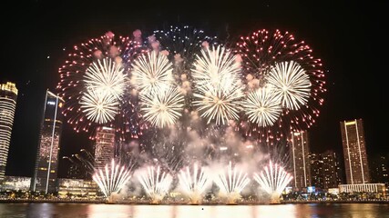 Fireworks bursting in vibrant colors light up the night sky over a bustling urban cityscape, capturing the essence of celebration and revelry, perfect for conveying a sense of community and.