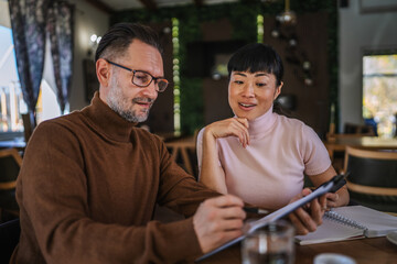 Diverse business colleagues reviewing documents during meeting in restaurant
