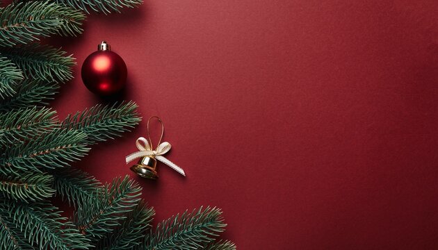 Christmas flat lay with fir branches red bauble and golden bell on a red background with copy space.