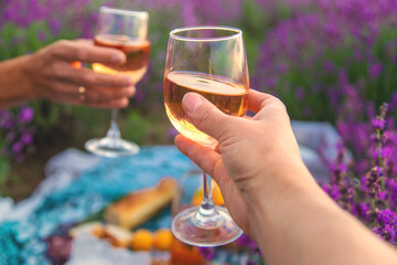A woman and a man drink wine in a lavender field. Selective focus.