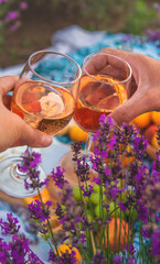 A woman and a man drink wine in a lavender field. Selective focus.