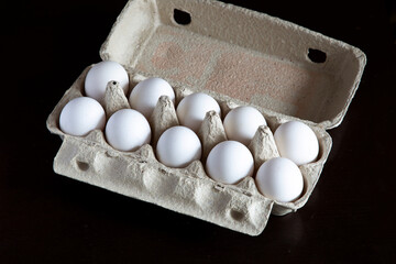 a dozen chicken eggs in a package on a black table