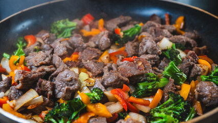 Beef strips sizzling with broccoli, bell peppers, and onions in a dry fry. Golden brown, juicy, and perfectly cooked for a healthy meal.