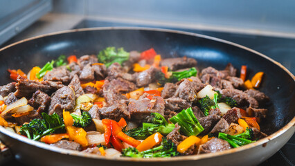 Beef strips sizzling with broccoli, bell peppers, and onions in a dry fry. Golden brown, juicy, and perfectly cooked for a healthy meal.