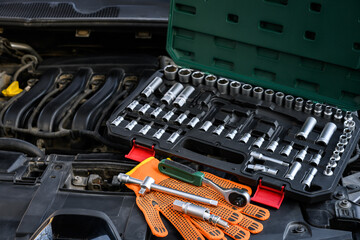 Auto mechanic tools under the open hood of the car