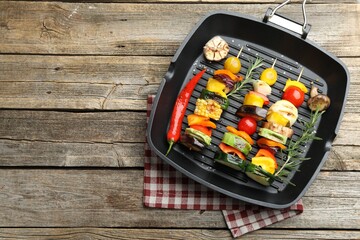 Grill pan with tasty vegetables on wooden table, top view. Space for text