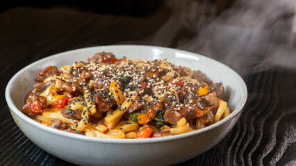 Smoking hot beef udon with broccoli, onions, and bell peppers in a beautiful bowl. Rich broth, fresh vegetables, perfect for Japanese cuisine lovers.