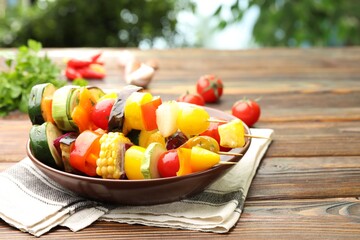 Skewers with tasty grilled vegetables on wooden table. Space for text