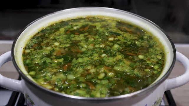 Fresh vegetable soup is boiling in a saucepan, hot steam rises up