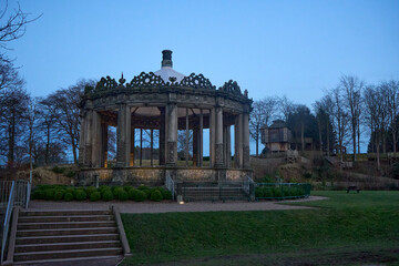 Fototapeta premium A serene evening at Dalkeith Park reveals a weathered bandstand beside the River Esk, framed by bare trees.