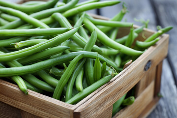 Obraz premium Freshly picked green beans in wooden basket, close-up textures and natural imperfections, outdoor light, 
