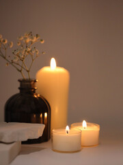 Selective soft focus Burning blur candles with flower in vase and stones podium. Evening night Light and shadow gray neutral background. Minimalist still life.