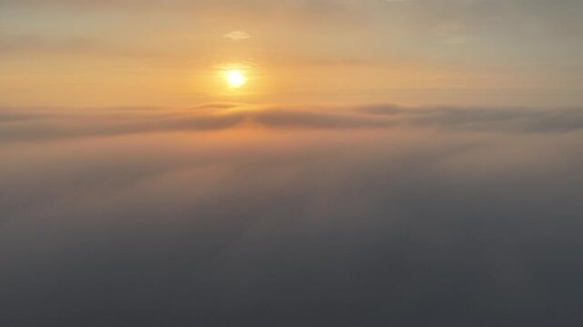 Cinematic aerial video of church tower rising from low passing clouds and fog during sunrise in the city of Utrecht, the Netherlands