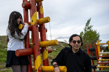 Happy Child Climbing Playground Structure with Dad Watching in Park