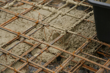 Rebar grid of a foundation being filled with liquid concrete at a construction site