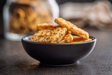 Crunchy salted crackers in bowl on black table.