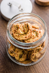 Crunchy salted crackers in jar on wooden table.