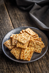 Crunchy salted crackers on plate on wooden table.