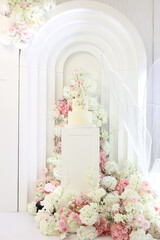 baby celebration setup with white arches, pedestal cake, and pink white florals. Concept: premium baby shower or christening event styling. Ideal for planners, decor brands, venues, and ads. 