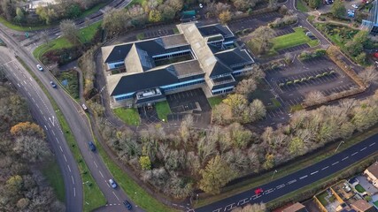 Aerial drone footage of an abandoned office building in a business park in North Swindon, UK. The video captures the derelict structure, empty parking areas, and surrounding suburban commercial enviro