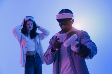 Team Young African male and Asian female engaging in virtual reality gaming experience, neon light