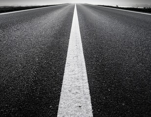 photo of a black and white closeup of an asphalt road with white lane markings leading towards a vanishing point symbolizing journey and progress