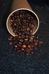 Fresh roasted coffee beans spilled from a glass onto the table