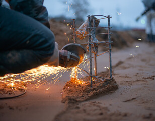 A person saws a reinforcing cage for a future concrete structure. Construction site in the evening. High quality photo