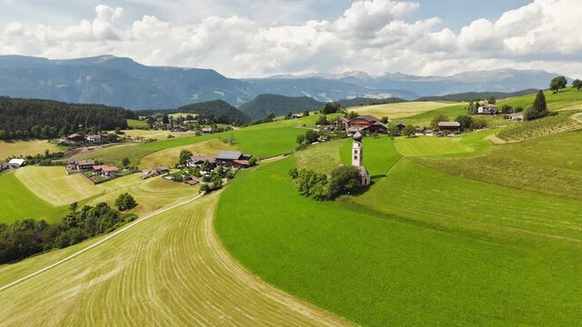 Church of Saint Valentine set by meadows on Seiser Alm, Dolomites, aerial view. Rural religious site on an alpine plateau