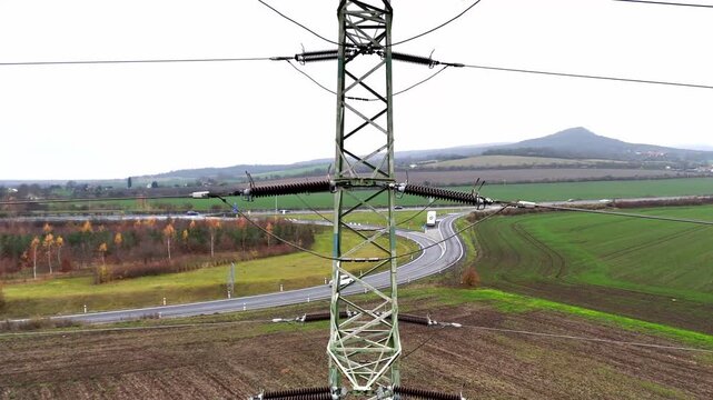 Aerial drone view of power transmission lines stretching across open terrain, tall pylons and cables forming strong linear patterns that highlight energy distribution and industrial landscape.
