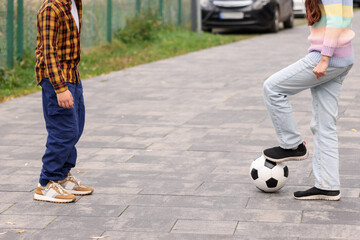 Little girl and boy playing with ball on pavement outdoors, closeup. Children in danger