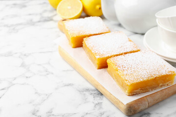 Tasty lemon bars with powdered sugar served on white marble table, closeup. Space for text