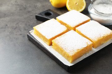 Tasty lemon bars with powdered sugar on grey table, closeup. Space for text