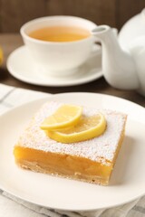 Tasty lemon bar with powdered sugar served on table, closeup