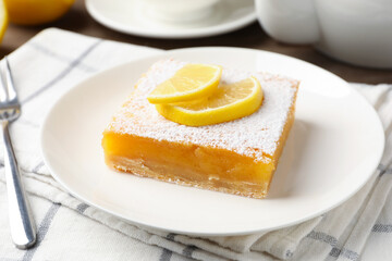 Tasty lemon bar with powdered sugar served on table, closeup