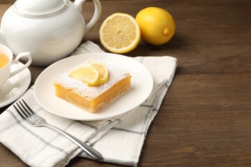Tasty lemon bar with powdered sugar served on wooden table, closeup. Space for text