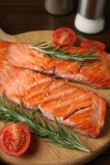 Pieces of tasty grilled salmon, rosemary and tomatoes on table, closeup