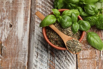 Dry basil leaves and fresh ones on color wooden table, flat lay. Space for text