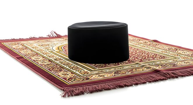 Black Muslim prayer cap and traditional red prayer mat on white background, symbolizing Islamic faith and worship.