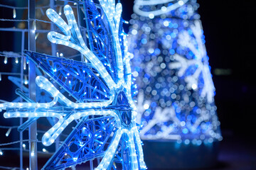 A bright LED snowflake shines with blue and white holiday lights. Soft bokeh and twinkle effects...