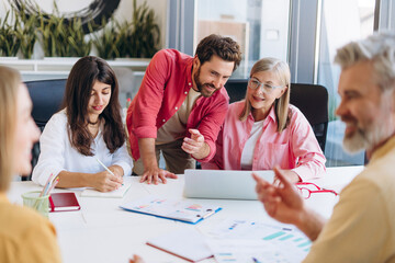 Diverse group of multinational team working in modern office planning project sitting on workplace