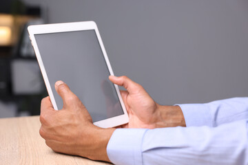 African-american man using tablet at wooden table indoors, closeup