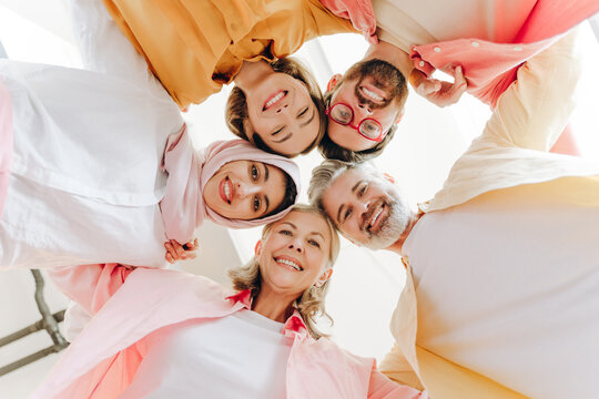 Diverse group of happy multinational women and men embracing looking at camera, teamwork concept