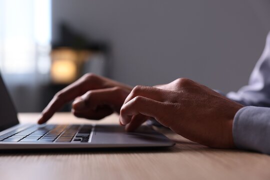 African-american man using laptop at wooden table indoors, closeup - Powered by Adobe