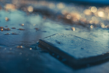 The dark ice in layers in a puddle reflects the dark blue sky. The usual winter background is macro...