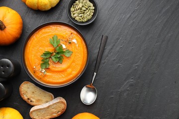 Tasty pumpkin cream soup with parsley in bowl served on grey table, flat lay. Space for text