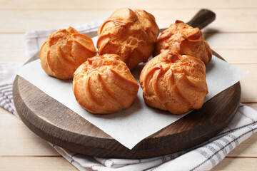 Delicious profiteroles on white wooden table, closeup